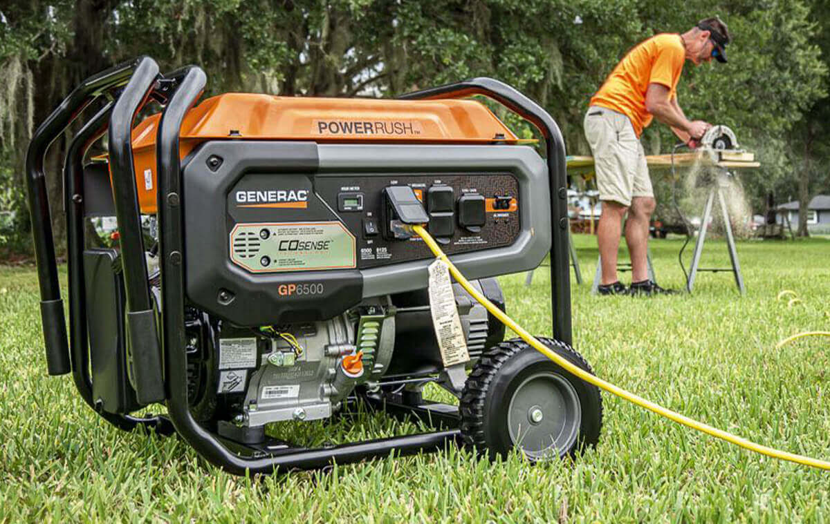 A man using a portable generator to saw wood in the middle of his backyard