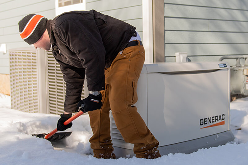 A man shovels fresh snow away from the perimeter of a whole-house generator on the side of his home